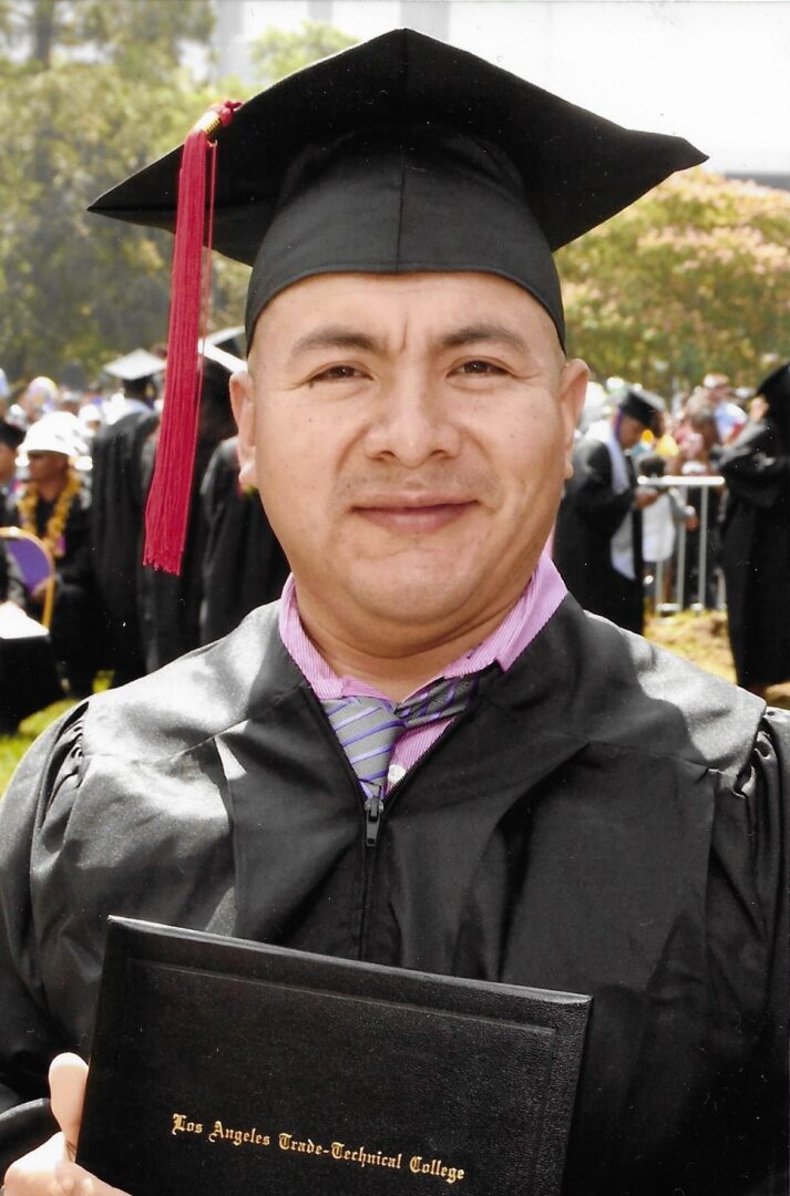 A man in graduation attire holding his cap.