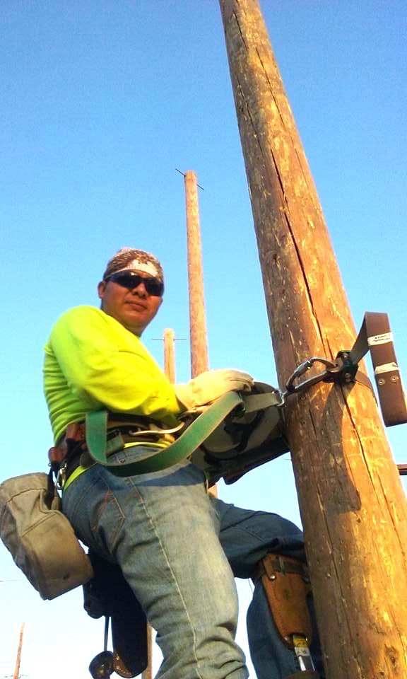 A man is climbing up to the top of a pole.